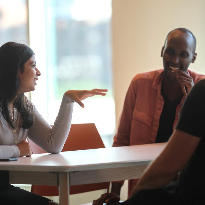 Group of graduate students laughing at table