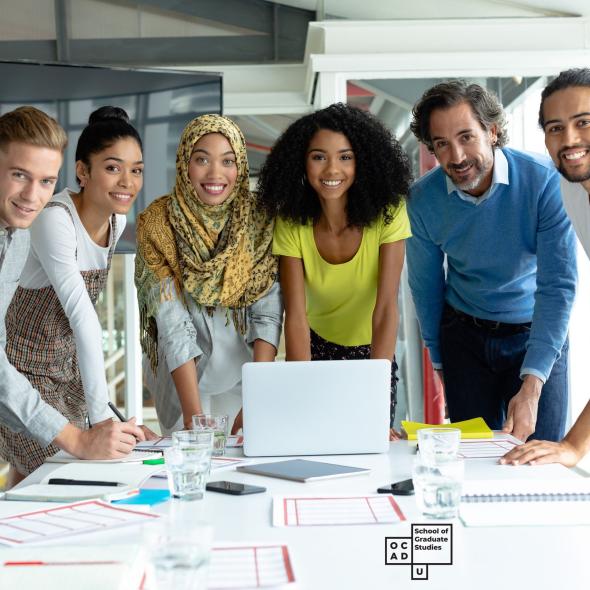 Group of students gathered around laptop, smiling